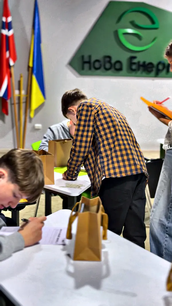 Підлітки працюють за столом під логотипом Нової Енергії